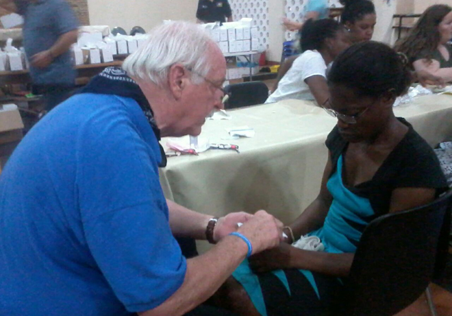 Past Director of Lions Clubs International, Dr Bill Iannaccone (left) attending to a woman in Kumasi.