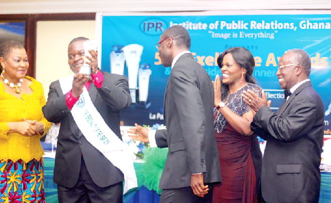  Mr Gayheart Mensah holds aloft his award as Mr Kojo Yankah (left) and Ms Joyce Aryee applaud him