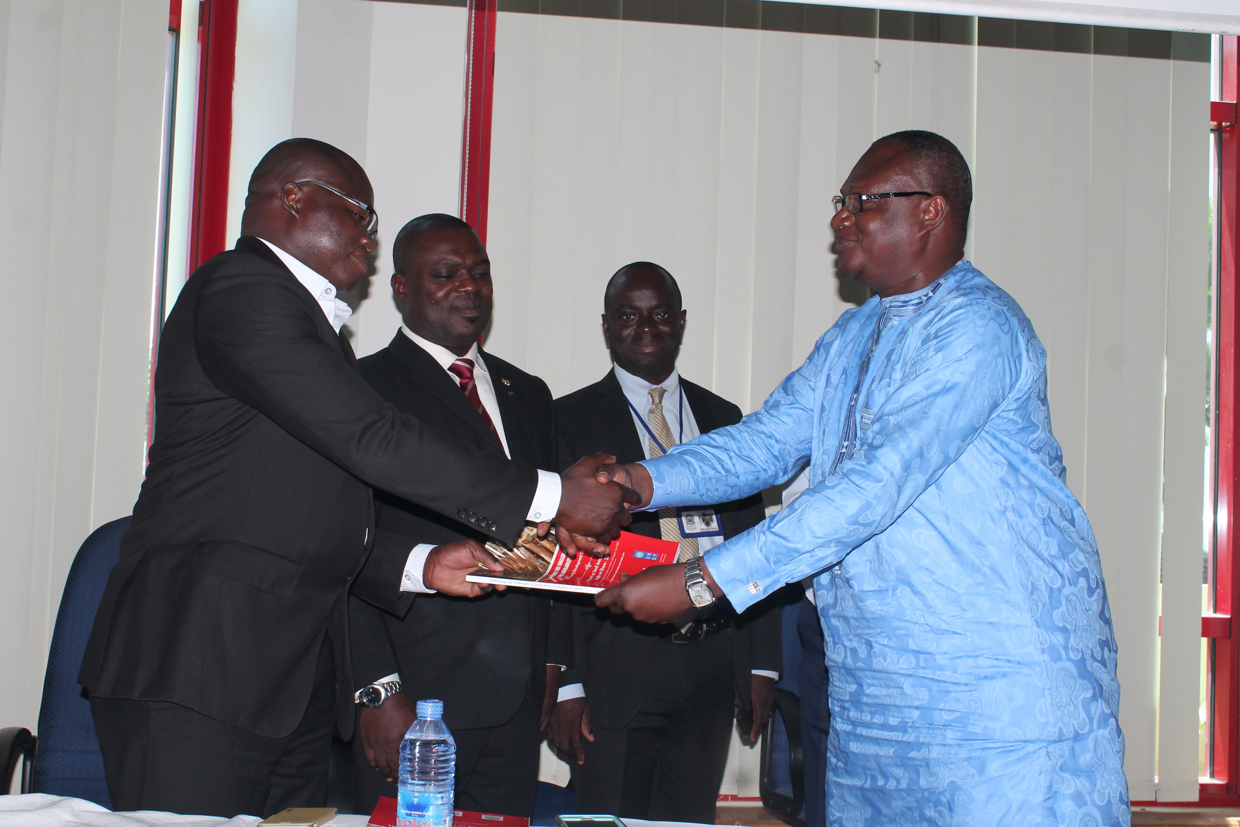 Mr Prosper Bani (right), the Minister of the Interior, presenting the report to Mr Louis Kuukpen (left), Assistant Country Director, UNDP. Looking on are Mr Jones Bortey Applerh, Executive Secretary of the Commission on Small Arms and Mr John Pokoo, Head of Conflict Management Programme
