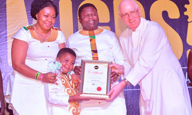 Rev. Father Andrew Campbell, the Parish Priest of Christ the King Catholic Church, presenting the award to Dr Dogbatsey, supported by  Mrs Juliana Adyzie Dogbatsey, the Administrator of the centre.