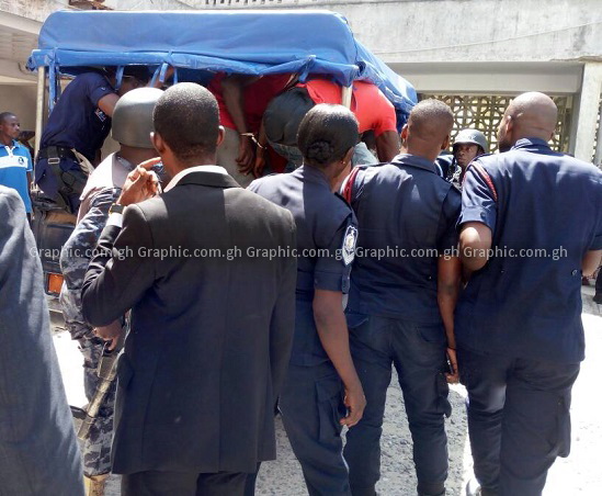 Security personnel ensuring that the suspects find space in the vehicle