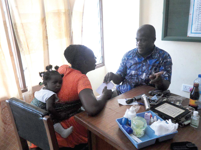 Mr Joseph Ankomah educating a lactacting mother after examining the eyes of both mother and baby during the exercise
