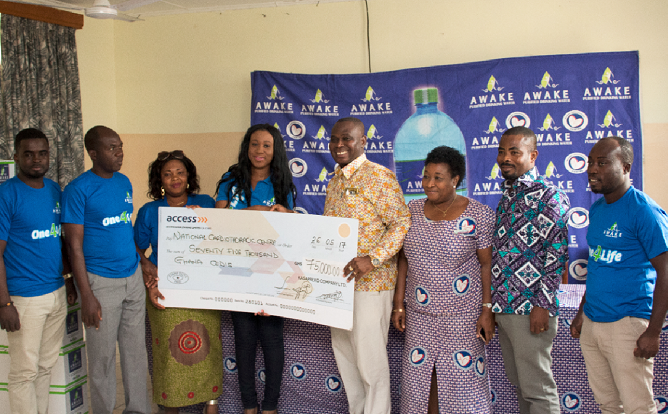 Dr Lawrence Sereboe receiving a dummy cheque from the Awake Purified Water team