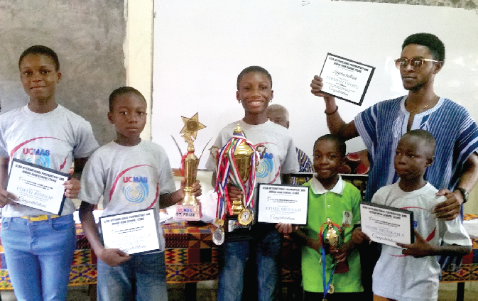 Pupils of the Star International School together with their UCMAS coach displaying their trophies and plaques.