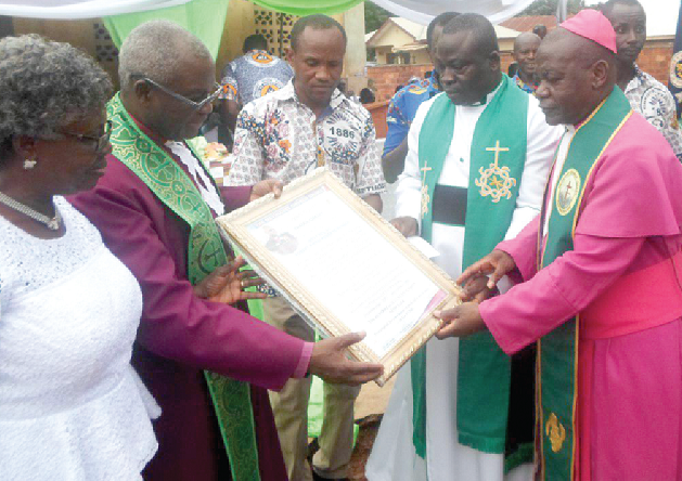  Rt Rev. Asare-Bediako (right), the Bishop of the Sunyani Diocese of the Methodist church, presenting a citation to the Most Rev. Dr Aboagye-Mensah while Mrs Grace Aboagye-Mensah (left) and others look on.