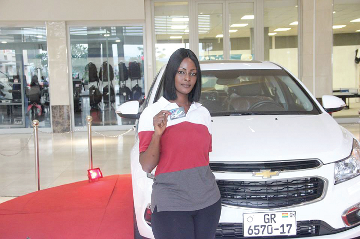  A promo finalist displays her card by the car she hopes to win on Republic Day