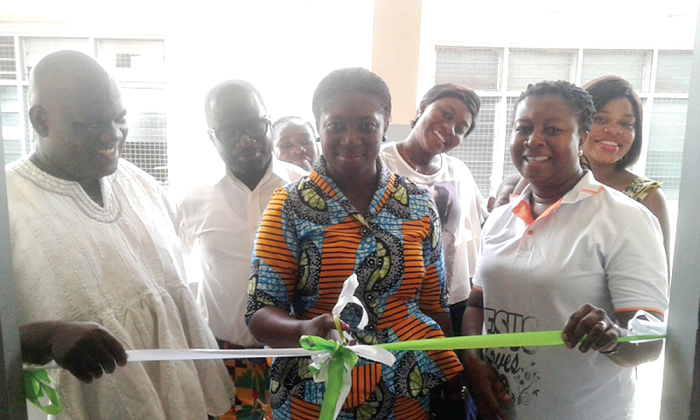 • Madam Evelyn Kuma Osei Owusu (middle)) cutting the tape to inaugurate the new library at the Kumasi children's home while Mrs Amponsah and others look on