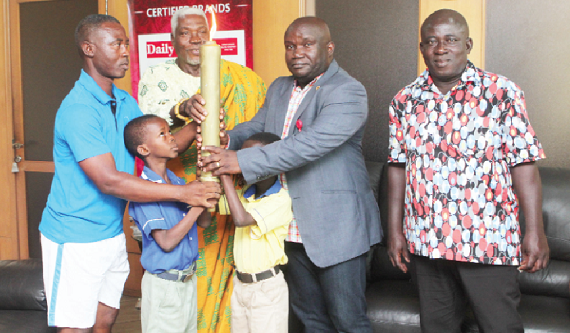 Mr Harry Ahorlu (left),Child Labour Ambassador, presenting the campaign torch to Mr  Kenneth Ashigbey (2nd right),Those with them include Torgbui Gobah Tengey (2nd left). Picture: EMMANUEL ASAMOAH ADDAI