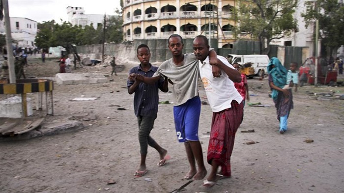 A wounded man is assisted after the suicide car bomb attack on Tuesday [Farah Abdi Warsameh/AP]