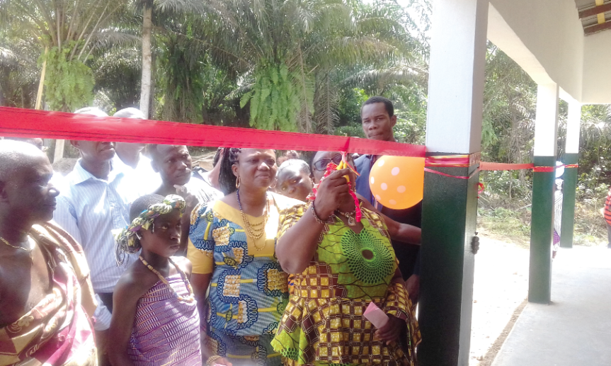 Ms Victoria Addai cutting the tape for the inauguration of the building as the CRAN administrator and members of the community look on.