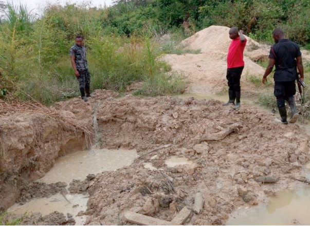 Mr Agyeman (middle) and a policeman inspecting the extent of damage caused by the galamseyers at Asuotiano