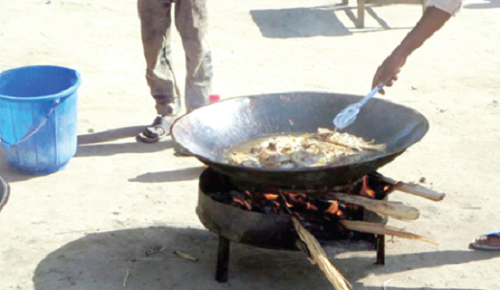 A food vendor frying fish for sale