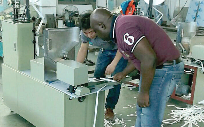 Mr Kenneth Okine (right) demonstrating how one of the machines cut the bamboo into toothpicks