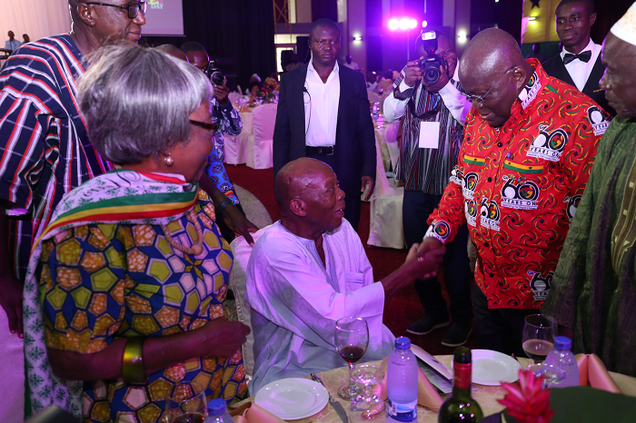 President Akufo-Addo tapping Mr Haruna Esseku (seated), a former Chairman of the NPP, during the 57th Republic Day in Accra. Looking on are some senior citizens