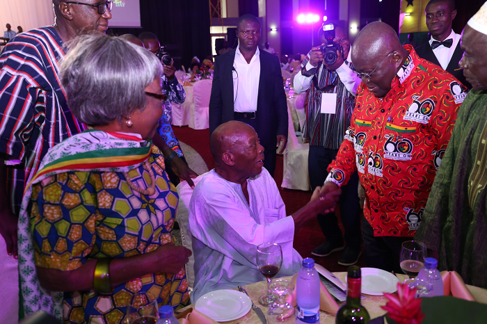 President Akufo-Addo tapping Mr Haruna Esseku (seated), a former Chairman of the NPP, during the 57th Republic Day in Accra. Looking on are some senior citizens 