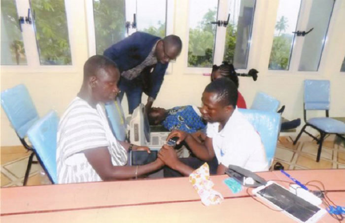 Dr Raphael Nyarkotey-Obu (standing, in glasses) and his team carrying out the screening of patients at Akyem Asene