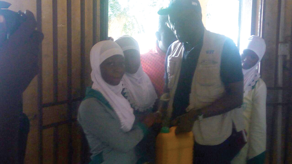 Mr Dieng, the WFP Regional Director for West and Central Africa, presenting the ration to one of the beneficiaries at the Nahdar Islamic School in Tamale during his visit.
