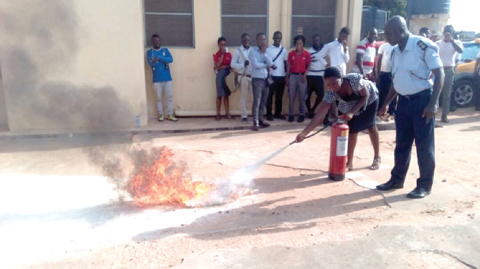 A fire officer (right) supervising a filling station attendant on how to use the fire extinquisher