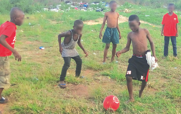 Some of the children playing football near the refuse dump