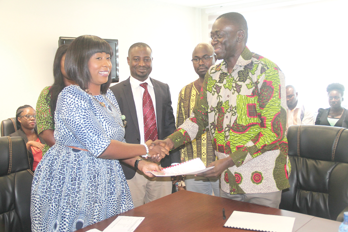 Mr Kofi Asante (right), Administrator, GIFEC, and Ms Lydia Atiemo (left), Deputy Chief Executive Officer incharge of Finance and Administration, YEA, exchanging documents after the signing ceremony. Picture: EDNA ADU-SERWAA