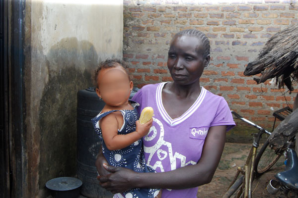 A woman holds her granddaughter who was fathered by a Chinese national working at Karuma hydropower dam. 