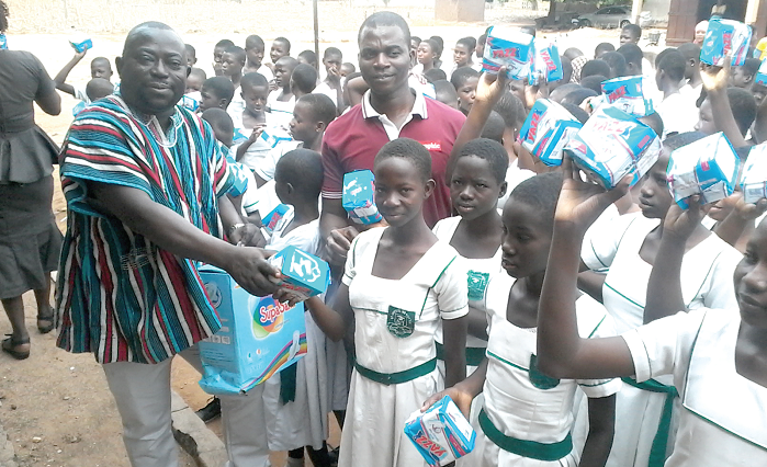 Mr Peter Ayamga (in smock) and Mr Azure Abdulai (in Polo shirt) distributing the sanitary towels to the girls of Saint Annes Roman Catholic JHS at Bongo
