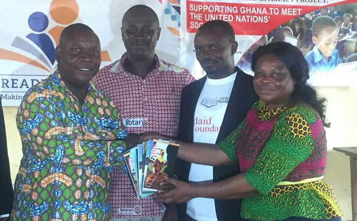 A teacher receiving books from the Rotary officials during the presentation exercise