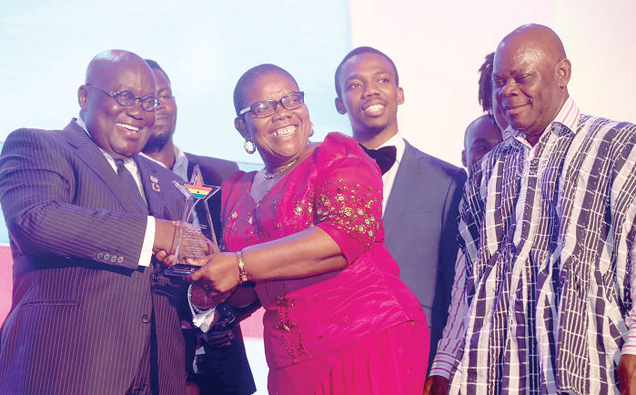 Mrs Bella Ahu, receiving the award from President Akufo-Addo, while some of her staff members look on with admiration