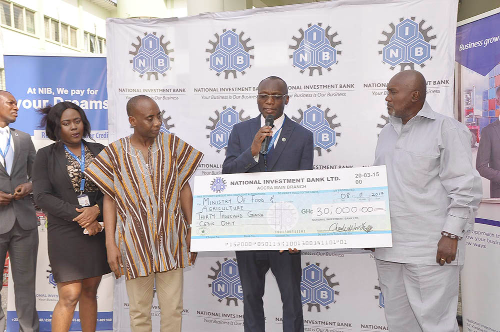 An official of the National Investment Bank (right) making a donation to Dr Sagre, a Deputy Minister of Food and Agriculture,  towards this year’s Farmers Day celebration