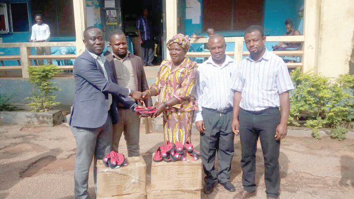 Mr Emmanuel Ntim (left) presenting the footwear to the Bosomtwe District director of education at Aputuogya