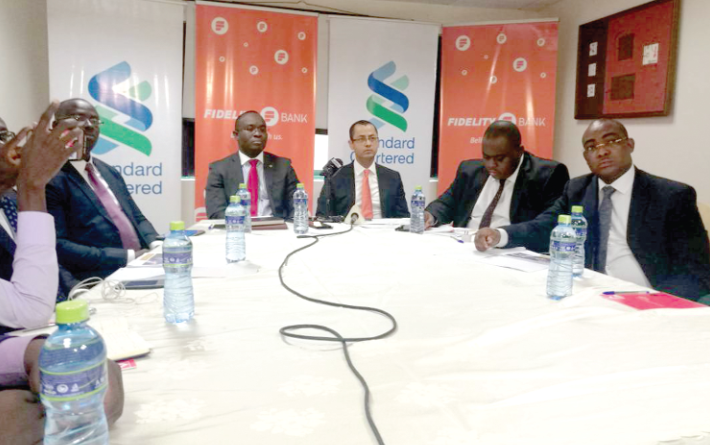 Mr Xorse Godzilla (left, head of table) from Standard Chartered Bank and Mr Samuel Aidoo (right) from Fidelity Bank jointly addressing the press conference in Accra.