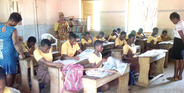 Some students of the Akosa MA JHS 1 going through pages of the Junior Graphic 