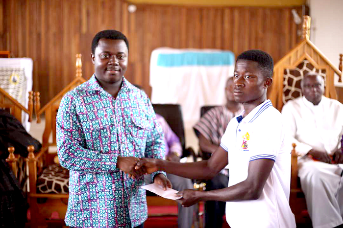 Rev. John Ntim Fordjour (left) presenting a scholarship package to one of the beneficiaries 