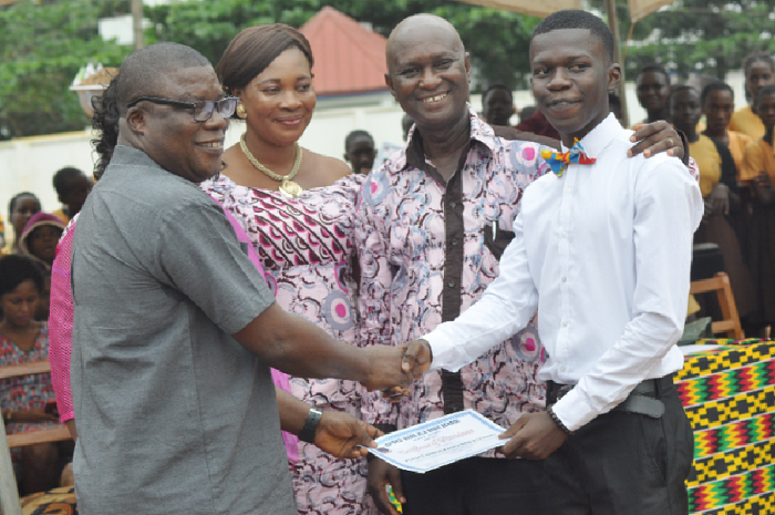  An Educationist, Mr Eugene Asante-Bekoe (left), presenting a certificate to Master Kelvin Asante-Bekoe (right), one of the graduates. Those looking on include  Mr Henry Appiah Boateng (2nd right), the Headmaster of the school.