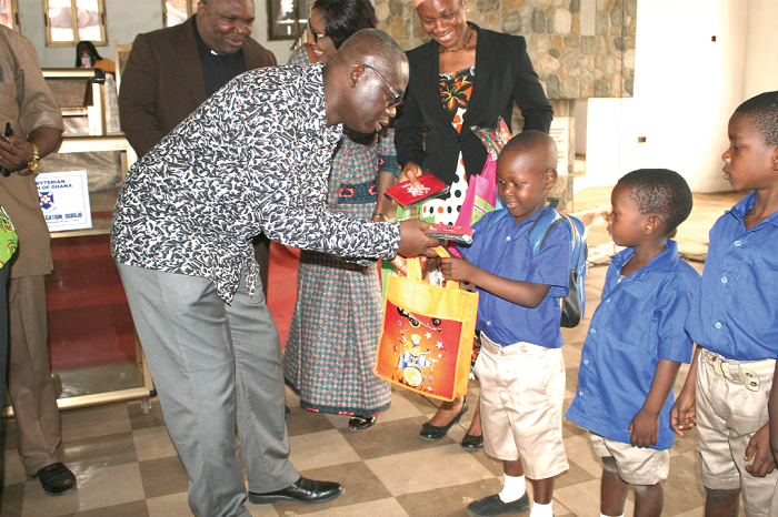 Prof Kwesi Opoku Amankwa (left), Director General of the Ghana Education Service, presenting some items to the children  during his visit to one of the schools