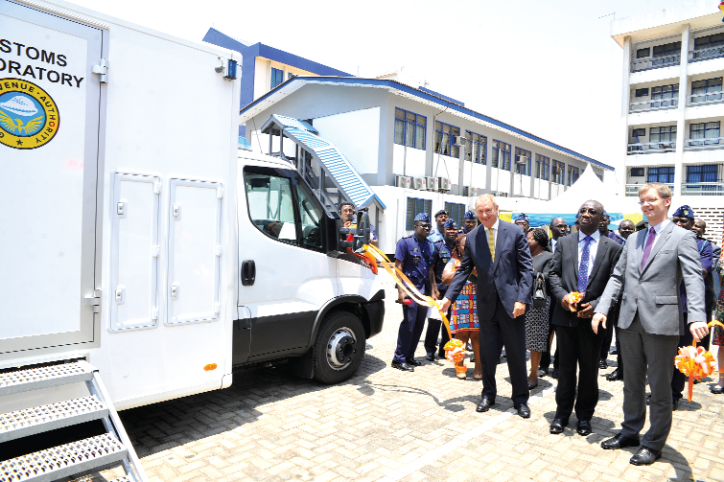 Mr Emmanuel Kofi Nti (2nd right) being assisted by Mr Ron Strikker (left) and Mr Hans-Helge Sander, Deputy head of Mission, German Embassy (right), to cut a tape to inaugurate the customs mobile laboratory vans.