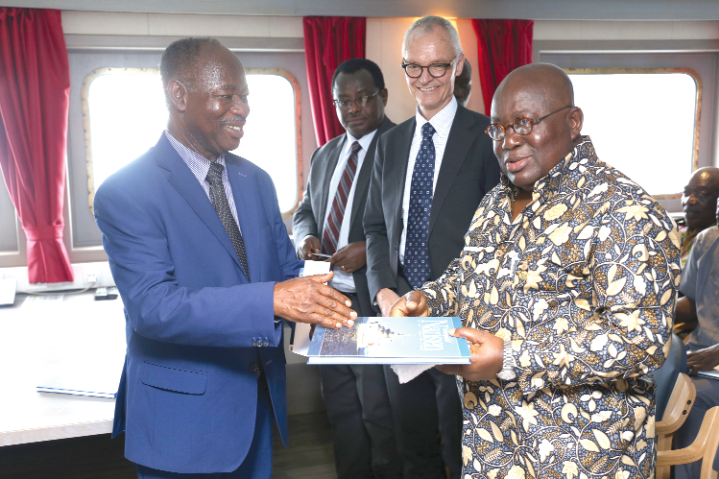 Dr Kwame Koranteng presenting a book on the research vessel to President Akufo-Addo after a tour of the vessel