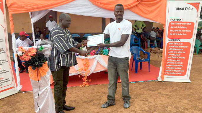 Mr Bingrini (in smock) presenting a certificate to a member of the Nkpeepa community which was declared free from open defecation