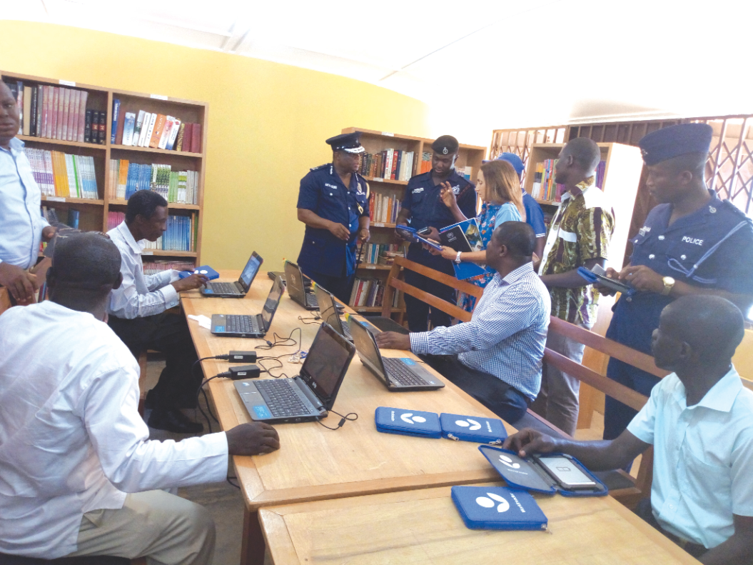 COP Ampah Bennin and Mr Tetteh Padi (seated 2nd right) using the electronic library at the Egyei-krom Refugee Camp