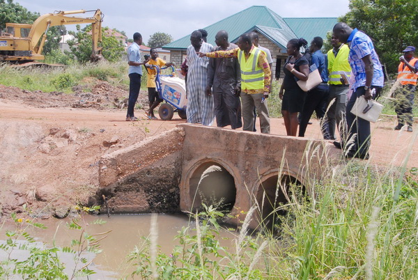 Nii-Noi Adumuah,(with hand stretched) inspecting a drainage at Amrahia Zongo.With him are the media and the officials from the Assembly