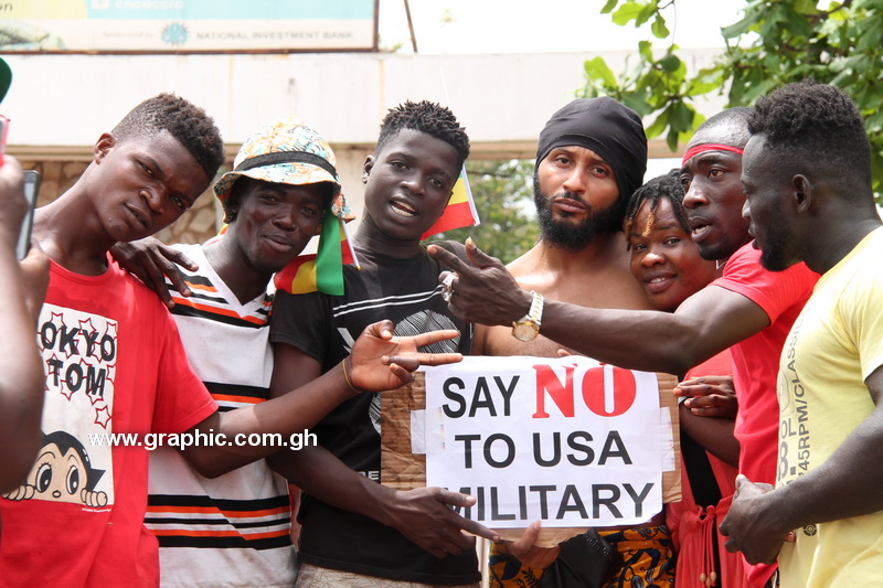 Demonstrators rally around one of the many placards during the demonstration against Ghana–US military deal