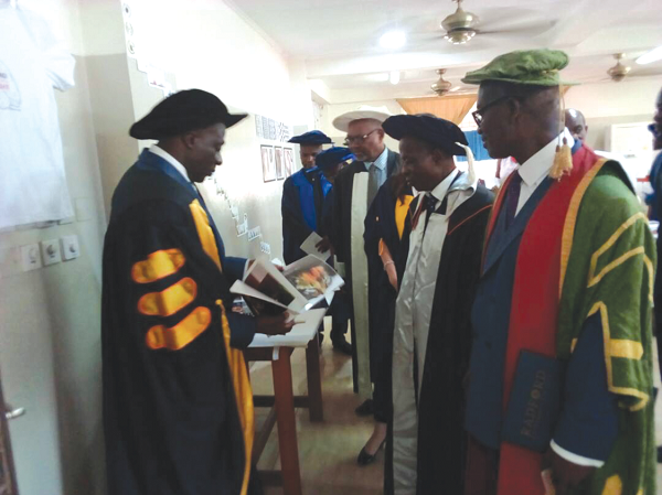 Nana Dwomoh Sarpong (left) displaying one of the works of the graduates to Rev. Prof. Charles Ansah, Pro-Vice-Chancellor of the Kwame Nkrumah University of Science and Technology (KNUST) (right), Dr Paul Effah (2nd right) and Emeritus Prof. D.E.K. Amenumey (3rd right)