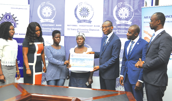 Mr Charles Wordey (3rd right), Head of Corporate Affairs, NIB, presenting a dummy cheque to Madam Rose Biney and Patience Addo. With them are some officials of Global Outreach Consortium and NIB