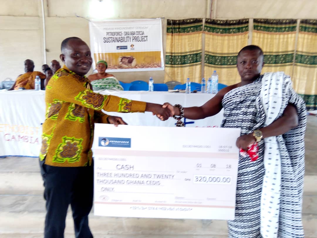 The sector Manager for Petroforce-Sika Aba , Mr Thomas Andoh (left) presenting the dummy cheque to the Kyidomhene of Gambia No.2 on behalf of the cocoa farmers 