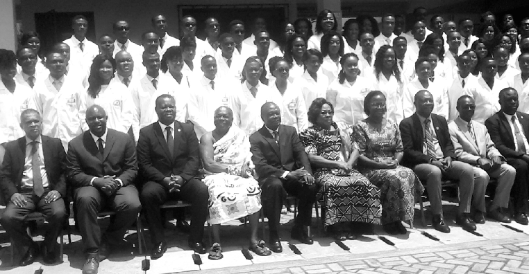 Student doctors in their white coats with dignitaries after the ceremony