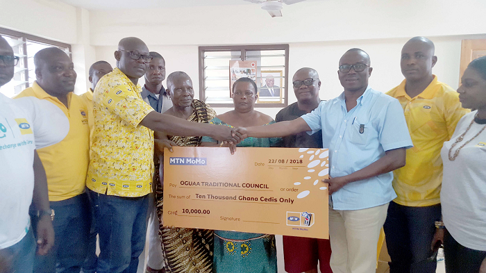 Mr Simon Amoh (left), the Regional Senior Manager of MTN Ghana South West Business District, presenting a dummy cheque to Mr Perry Mensah (3rd right), the Chairman of the 2018 Oguaa Fetu Afahye Planning Committee 
