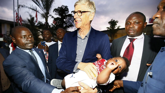 Arsene Wenger holds his baby namesake on arrival in Liberia 