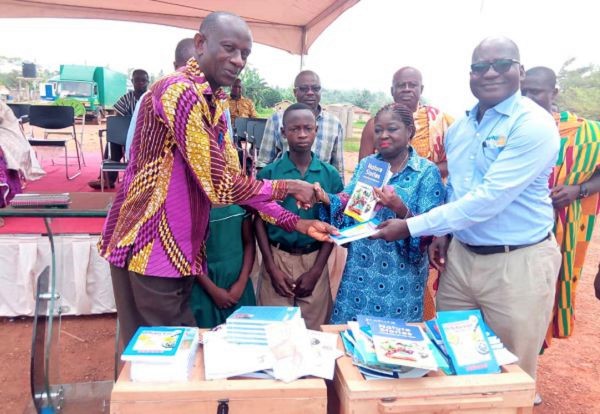 Mr  Shadrach Ainoo (right) of Asanko Opportunity together with the Executive Director of the Ghana Book Trust Fund, Mrs Genevieve Polley presenting some of the books to the Headmaster of Manso Abore (R/C) School, Mr Augustine Boakye Mensah. The School is one of the beneficiaries of the project