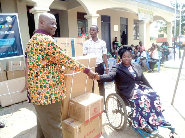 The District Chief Executive (DCE), Mr Adzoteye Lawer Akrofi, presenting an item to Ophelia Okutu, a physically challenged person 