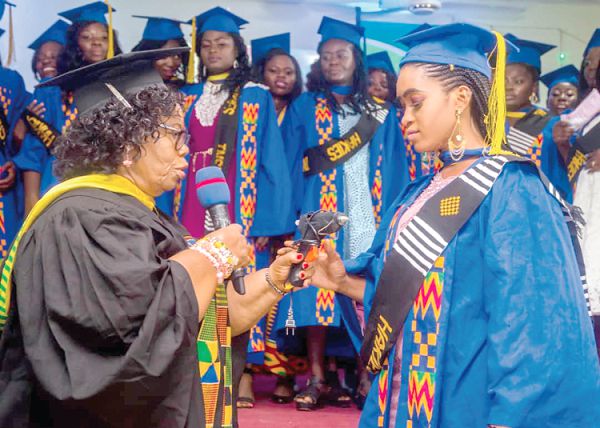 The Board Chairperson of Hakies Floral and Catering Institute, Madam Esther Happy Edjeani, speaking to one of the graduands, while the others look on